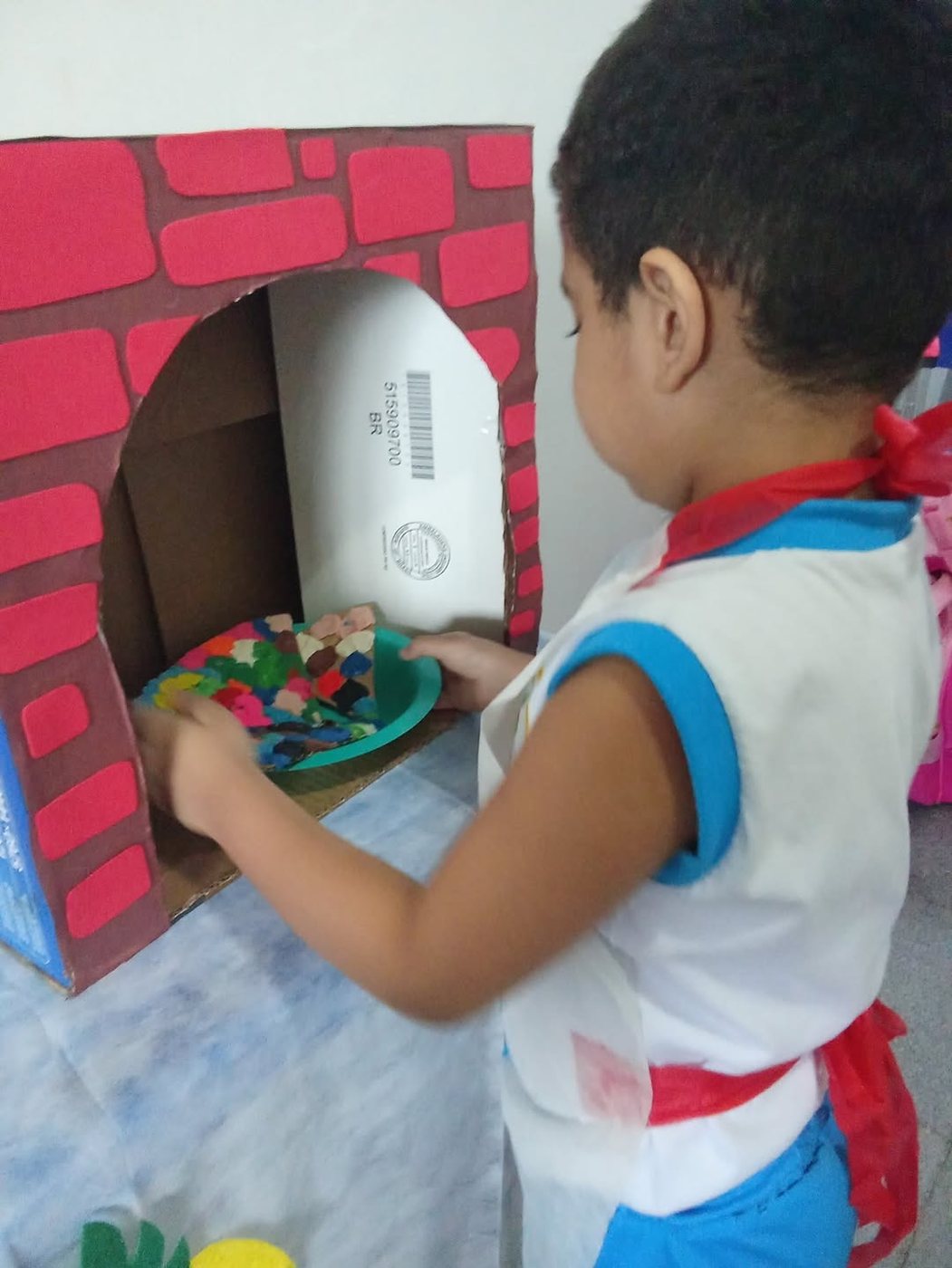 Criança preparando pizza de massinha na oficina de culinária